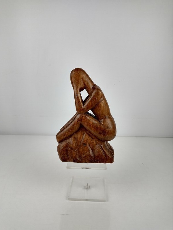 Handgesneden houten beeldje van zittende figuur in denkende houding.